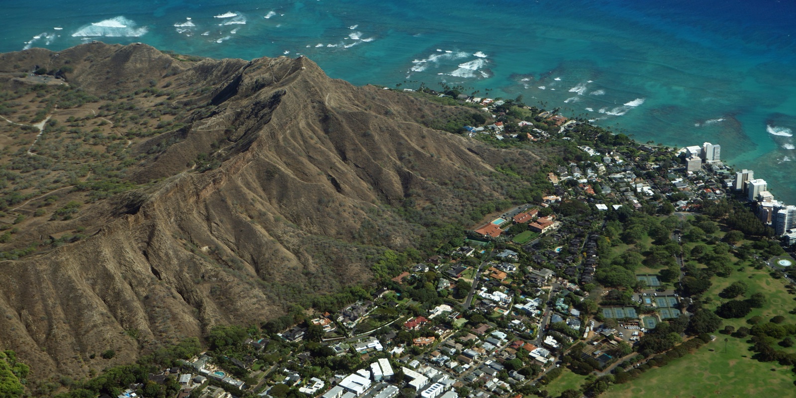 Aerial view of Diamond Head crater with the Gold Coast neighborhood and Waikiki high-rises along the shoreline
