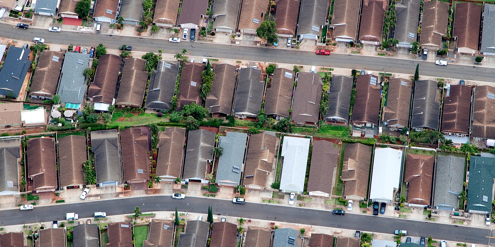 Aerial view of rows of single-family rooftops along curving suburban streets in an Oahu subdivision